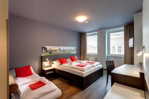 Zimmer mit 2 Betten, einem Tisch und einem Schreibtisch in der Unterkunft MEININGER Hotel Wien Downtown Sissi in Wien