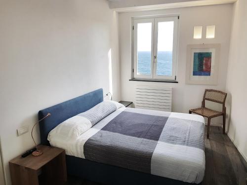 ein Schlafzimmer mit einem Bett, einem Fenster und einem Stuhl in der Unterkunft Fivestay Casa Gabriella in Vernazza