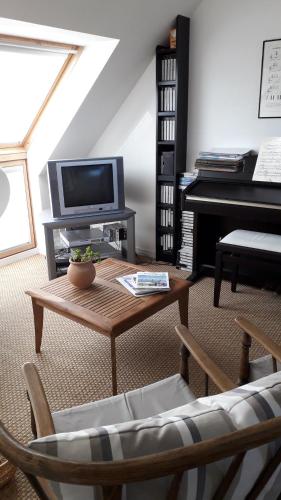 ein Wohnzimmer mit einem Klavier und einem Couchtisch in der Unterkunft Chambre d'hôtes - La Maison de Jane in Jullouville-les-Pins