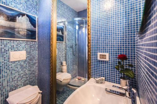 La salle de bains est pourvue de carrelage bleu, de toilettes et d'un lavabo. dans l'établissement Locazione Turistica Corte Vecchia, à Venise