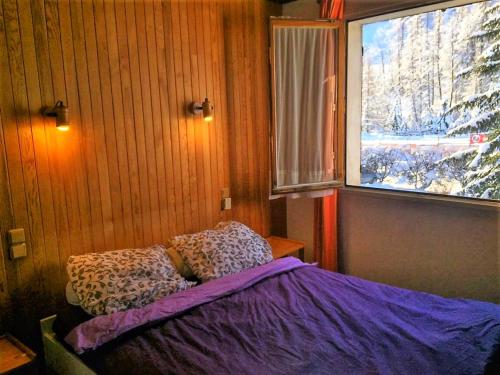 Un dormitorio con una cama con sábanas moradas y una ventana en Serre Chevalier -Cosy Apartment "Le Coolidge" for 7 down the slopes with stunning view en Saint-Chaffrey