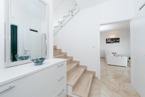a white staircase in a white house with a mirror at Villa Stani, luxury villa with a pool in Novalja