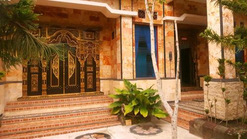 a building with a black door and some plants at HOTEL SEGARA MANDALA in Negara