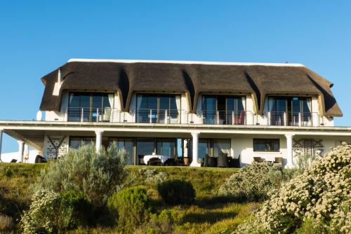 a thatch roofed house on top of a hill at St Francis Golf Lodge in St Francis Bay