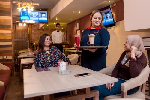 a woman standing next to two women sitting at a table at Havana Hotel Cairo in Cairo