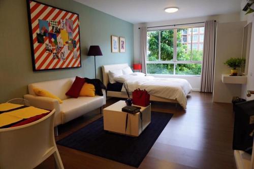 a living room with a bed and a couch at Baan Thew Lom Condo Cha am By PoPu in Ban Sahakham