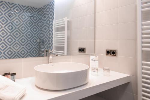 a white bathroom with a sink and a mirror at RVHotels Nieves Mar in L'Escala