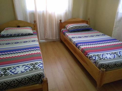 two beds in a room with wooden floors at Koinonia Retreat CenteR in Baguio