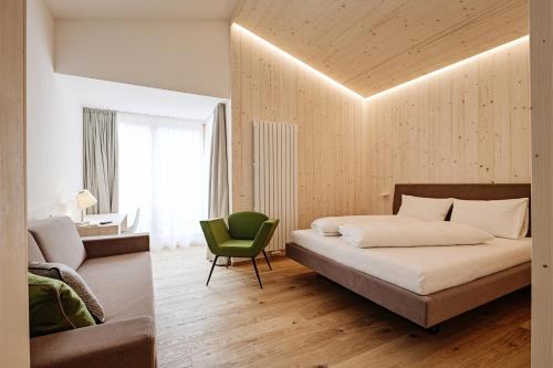 a bedroom with a bed and a green chair at Hotel Gertraud in Solda