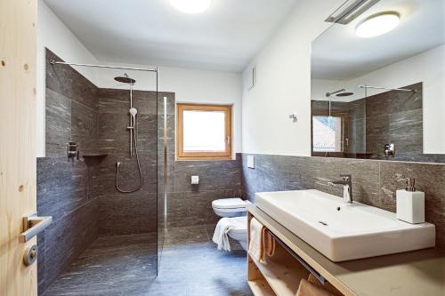 a bathroom with a sink and a shower and a toilet at Hotel Gertraud in Solda