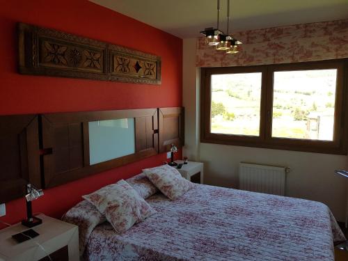 Un dormitorio con una cama con paredes rojas y una ventana en Apartamentos Ría de Villaviciosa, en Villaviciosa