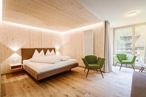a bedroom with a bed and two green chairs at Hotel Gertraud in Solda