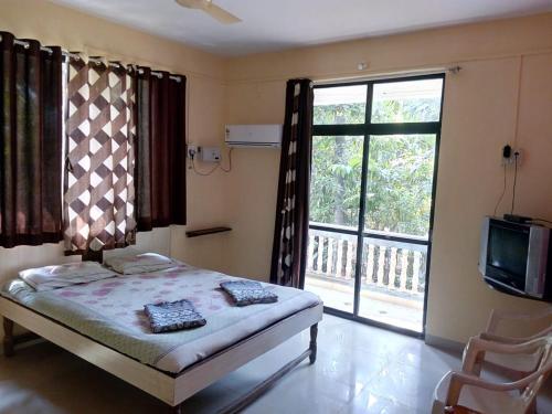a bedroom with a bed and a large window at Tendulkar Beach Resort in Diveagar