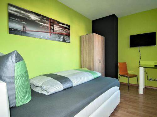 a bedroom with a bed with green walls and a tv at Ferienwohnung Nickmann im Scheffelhof in Bad Säckingen