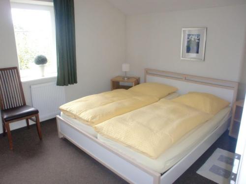 - un lit dans une chambre avec une chaise et une fenêtre dans l'établissement Ferienhaus-Utspann, à Lemkenhafen auf Fehmarn