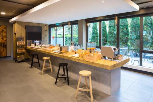 a large kitchen with a large counter with stools at ibis Zürich Messe Airport in Zürich