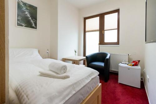 a bedroom with a white bed and a chair at Hotel Ungar in Svitavy
