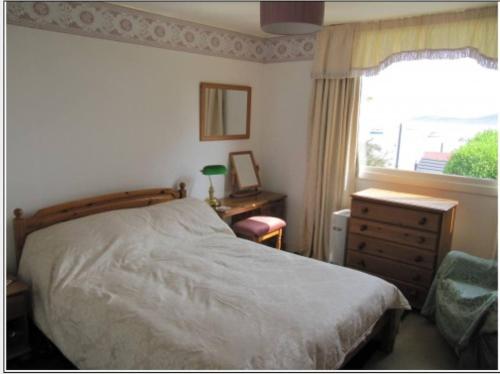 a bedroom with a bed and a dresser and a window at Braeside Craighouse Jura in Craighouse