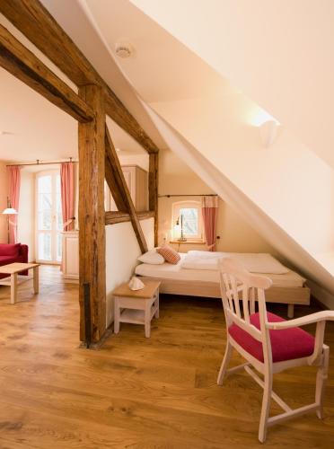 a attic bedroom with a bed and a chair at Hotel Gutshaus Parin - Bio- und Gesundheitshotel in Parin