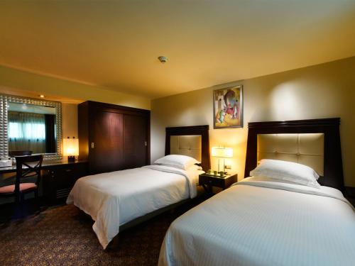 a hotel room with two beds and a desk at Raouche Arjaan by Rotana in Beirut