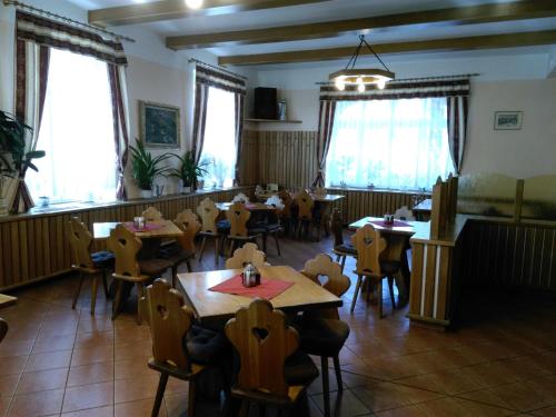 a dining room with tables and chairs and windows at Penzion Kneifel, s.r.o. in Horní Maršov