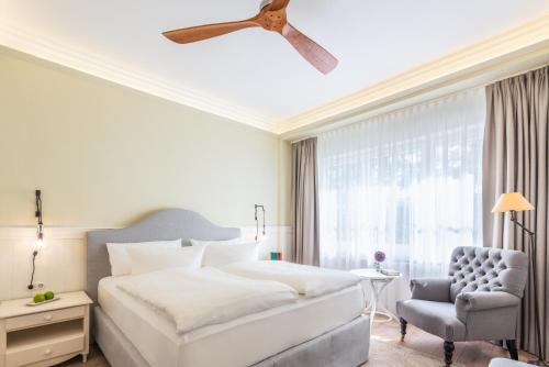 a bedroom with a bed and a chair and a ceiling fan at Strandhotel Ahlbeck in Ahlbeck