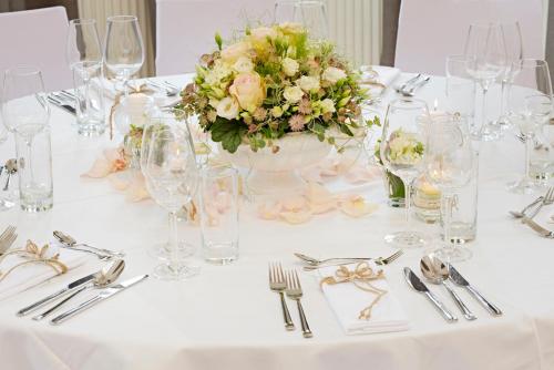 a table with a white table cloth with a vase of flowers at JUFA Hotel Stift Gurk in Gurk