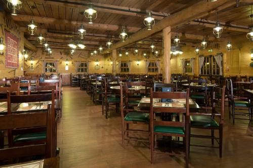 a restaurant with wooden tables and chairs and lights at Disney Davy Crockett Ranch in Villeneuve-le-Comte