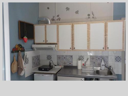 una cocina con armarios blancos y fregadero en G & G guesthouse en Edessa