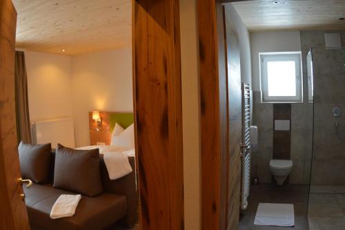 a room with a couch and a bed and a bathroom at Pension Alpenblick in Steeg