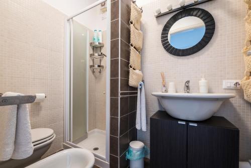 ein Badezimmer mit einem Waschbecken, einem WC und einem Spiegel in der Unterkunft Appartamento Balkissa in San Felice del Benaco