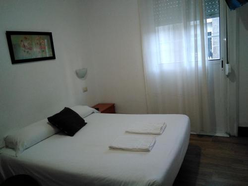 a bedroom with a white bed with towels on it at Hostal Ancla Dorada in Vigo