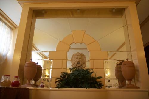 uno specchio su una mensola con vasi e un busto di Hotel Nuovo Rebecchino a Napoli