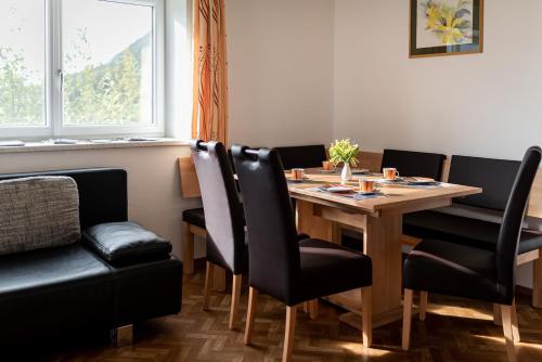 a dining room with a wooden table and black chairs at Ferienwohnungen Plattnerhof in Terfens