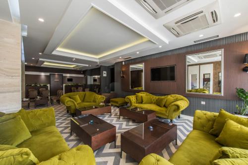 a lobby with yellow couches and tables at Garni Hotel Aveny in Čačak