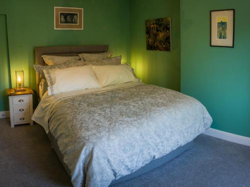 a bedroom with a large bed with green walls at Garden House in Masham