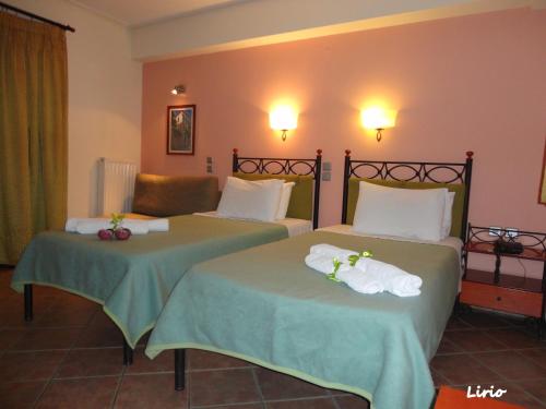 2 łóżka w pokoju hotelowym z ręcznikami w obiekcie Lirio Guest House w mieście Makrakómi