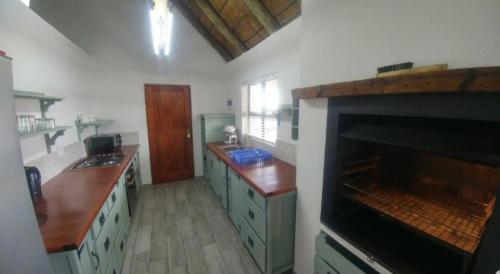 a kitchen with green cabinets and a fireplace at Breede River View with mooring at Witsand,Self-Catering Apartment in Witsand