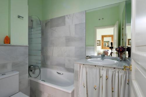 ein Badezimmer mit einem Waschbecken, einer Badewanne und einem Spiegel in der Unterkunft Veoapartment Miguel Terrace in Sevilla