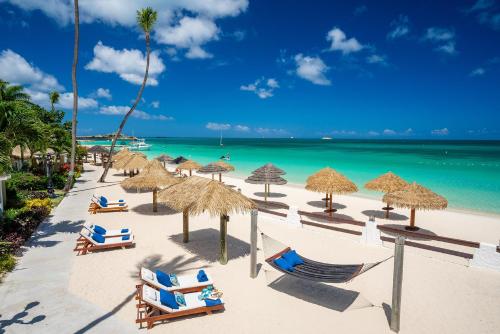 a beach with chairs and umbrellas and the ocean at Sandals Grande Antigua - All Inclusive Resort and Spa - Couples Only in Saint Johnʼs