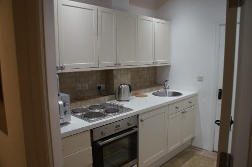 a kitchen with white cabinets and a stove and a sink at Bridgnorth B&B in Bridgnorth