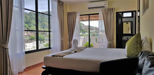 a bedroom with a bed and a large window at Karon Pool Hotel in Karon Beach