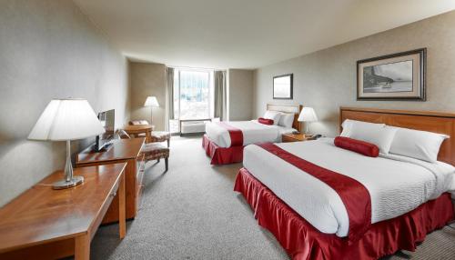 a hotel room with two beds and a desk at The Falls Hotel & Inn in Niagara Falls