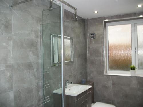 uma casa de banho com um chuveiro, um lavatório e um espelho. em Westpark Apartment em East Kilbride