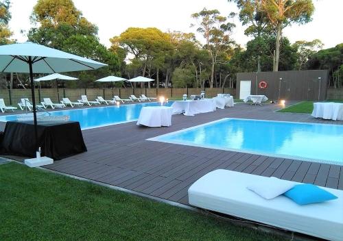 - une piscine avec des tables, des chaises et un parasol dans l'établissement INATEL Caparica, à Costa da Caparica