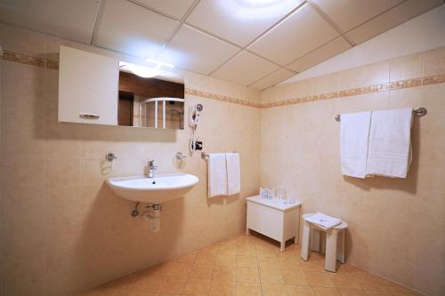 a bathroom with a sink and a toilet and towels at GH Hotel Fratazza in San Martino di Castrozza