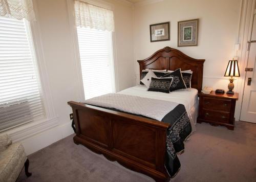 a bedroom with a wooden bed and two windows at New Orleans Hotel Eureka Springs in Eureka Springs