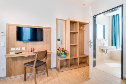 um quarto com uma secretária, uma televisão e uma casa de banho em Hotel Apfelrot em Erding