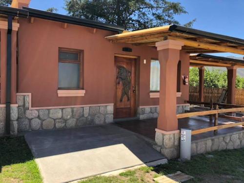 a home with a porch and a wooden door at El Viento De Mi Sueño in Tafí del Valle