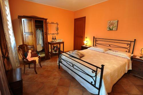 a bedroom with orange walls and a bed and a chair at Agriturismo Bianconiglio in Monforte dʼAlba